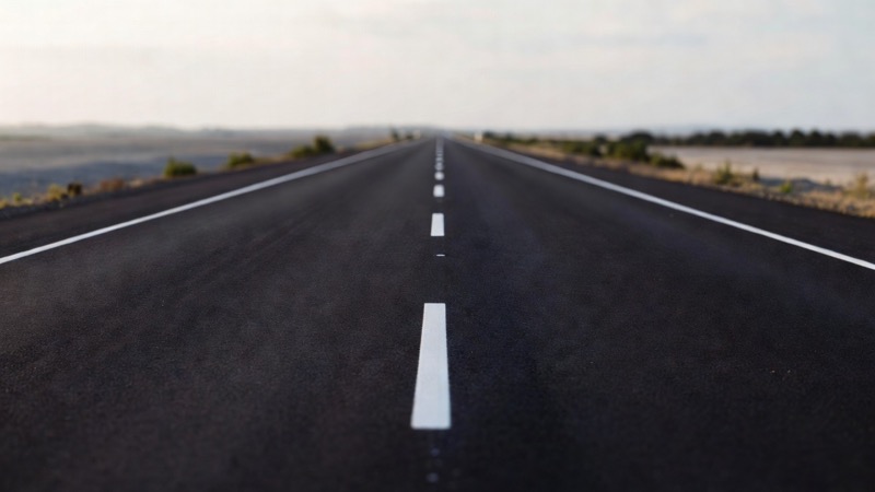An empty straight road with clear lane markings seen from a driver's viewpoint