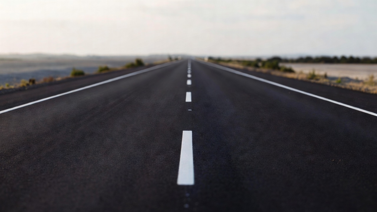 An empty straight road with clear lane markings seen from a driver's viewpoint
