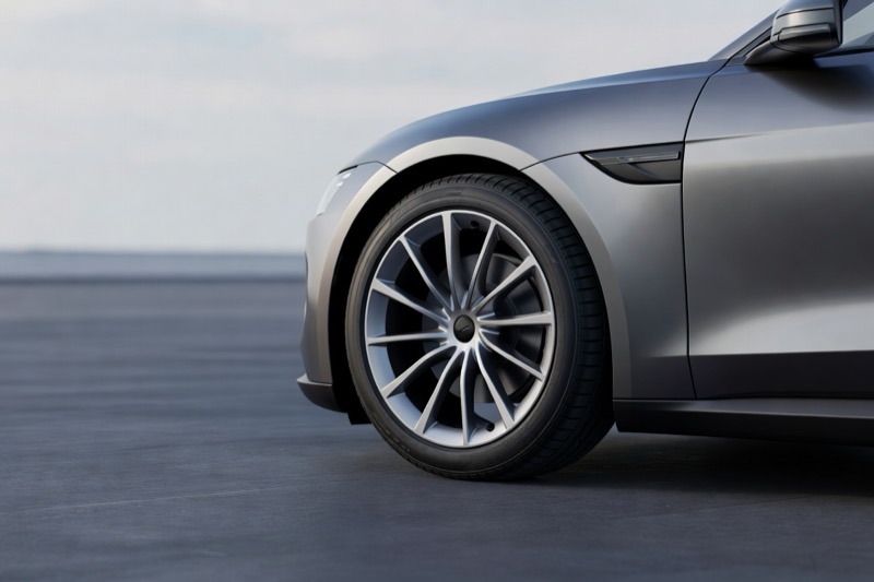 The front wheel and tyre of a modern electric car parked on clean tarmac