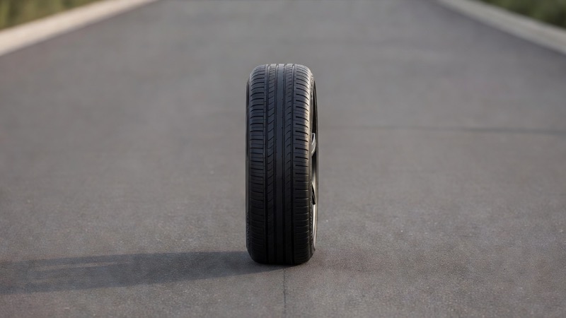 A car wheel and tyre photographed close up on a quiet road surface
