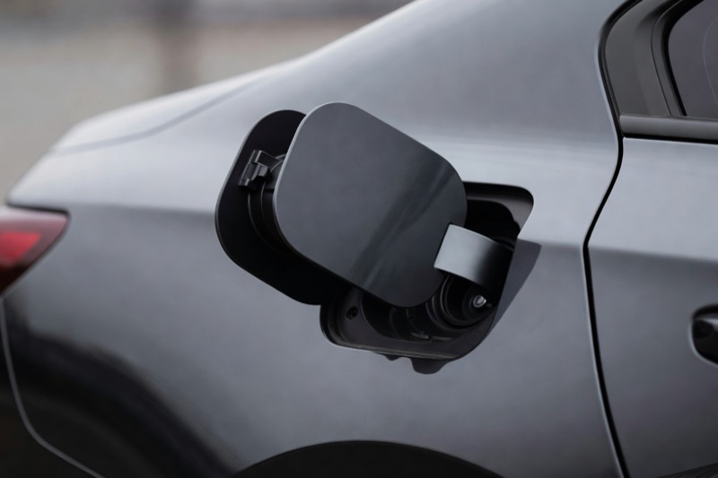 A fuel filler cap open on the side of a car in daylight